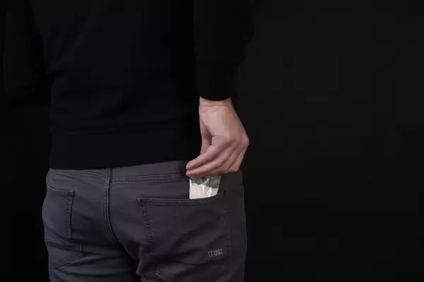 A man takes out a plastic bag from a pocket with a dose of cocaine or another concept of drugs