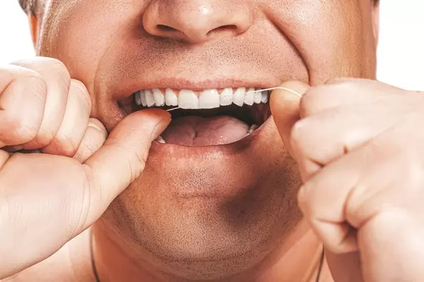 A man uses dental floss to clean his teeth