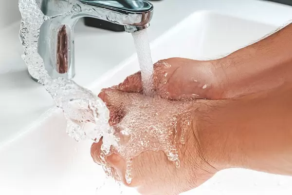 A man washes his hands under the tap in the bathroom