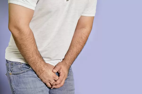 A man with hands holding his crotch. Man feels pain in his groin