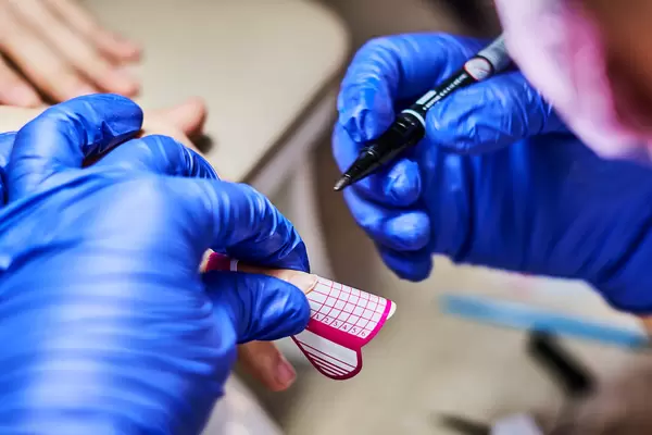 A master of nail polish puts a fixative on finger before making the nails gel in beauty salon
