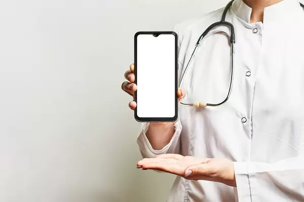 A medical worker holds a smartphone with a blank screen and copy space