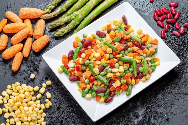 A mix of sliced colorful vegetables and whole on a black background. Top view (Flip 2019)