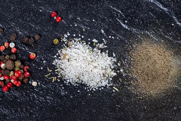 A mixture of peppers, ground black pepper and sea salt on a black background (Flip 2019)