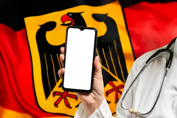 A nurse holding cell phone with empty screen over German flag