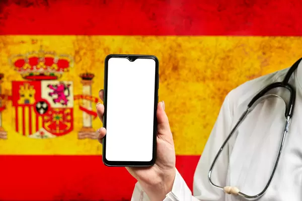 A nurse holding cell phone with empty screen over Spanish flag
