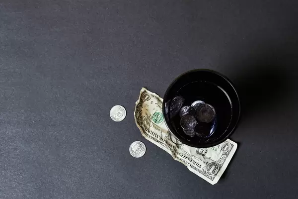 A paper cap of homeless with coins and money