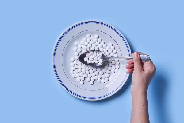 A person holding a spoon filled with medicines