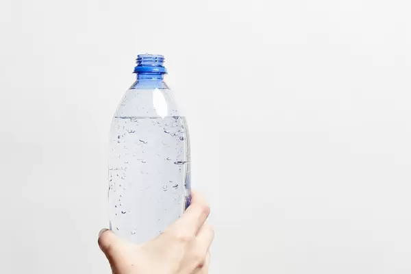 A person holds a bottle of sparkling water