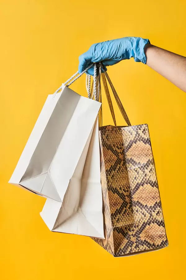 A person in medical gloves holding shopping bags
