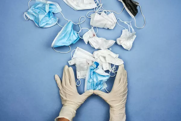 A person in medical gloves throwing away used face masks