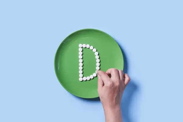 A person making Vitamin D text with medical pills