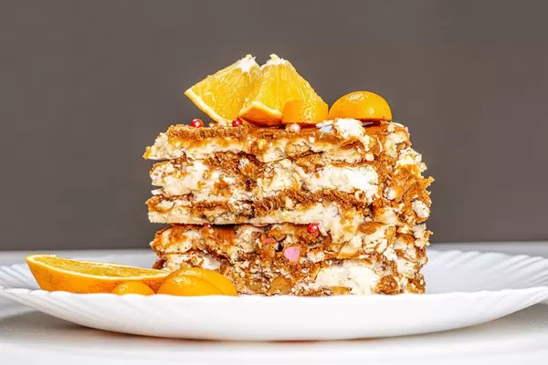 A piece of Kiev cake with condensed milk, nuts and citrus fruits
