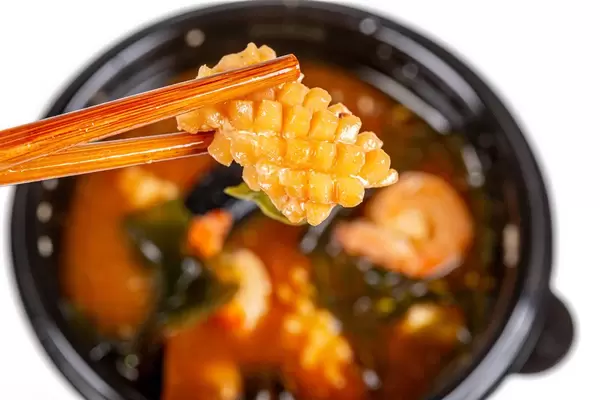 A piece of octopus in the wooden chopsticks, close-up