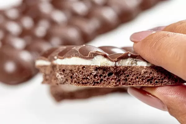 A piece of porous chocolate in a woman's hand closeup (Flip 2019)
