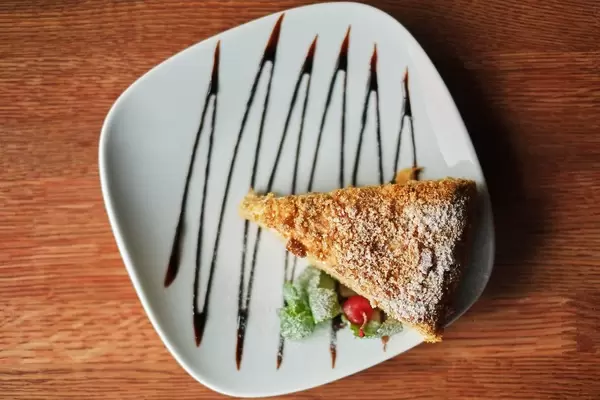 a piece of poured honey cake with chocolate topping on a plate, top view  Flip 2019