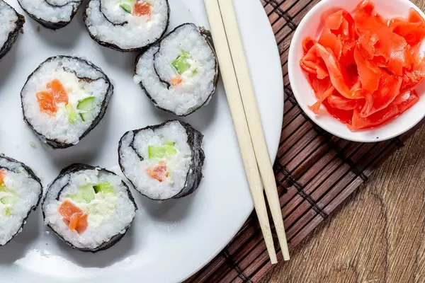 A plate of Maki rolls, chopsticks and ginger