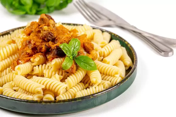 A plate of pasta with gravy and fresh basil leaves