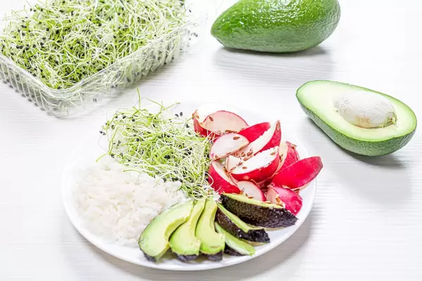 A plate of rice, radish, avocado and micro-greens onions on a white wooden background (Flip 2019)