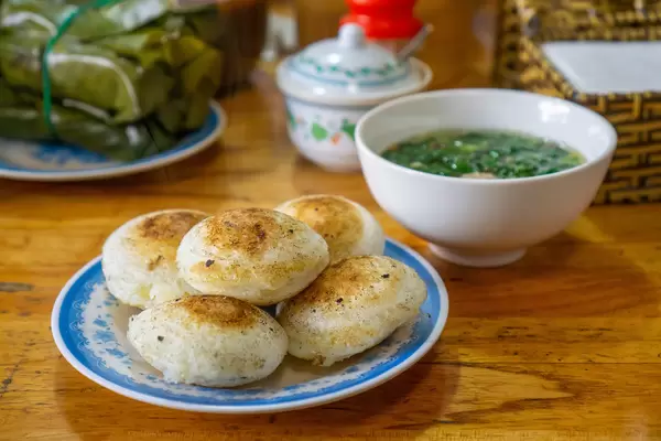 A Plate with Vietnamese Rice Cakes - Banh Can with a Bowl of Meatball Soup and Fermented Pork Rolls