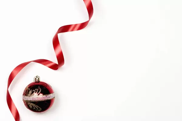 A red decorative Christmas ball and ribbon with on white background with copy space