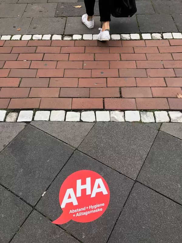 A red sticker with the Covid-19 tips in German: AHA (social distancing + hygiene + face mask)