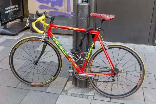 A red Tommasini Racing Bicycle secured to a post