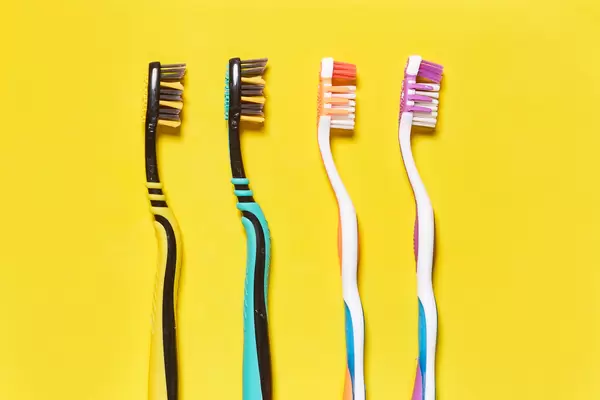 A row of toothbrushes on bright yellow background