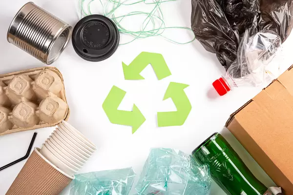 A selection of garbage for recycling, plastic, paper and glass with green waste recycling symbol, top view