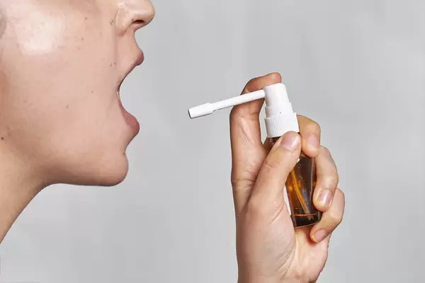A sick woman using spray for throat