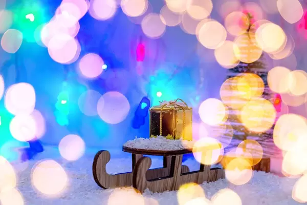 A sledge with a gift in the snow with a blurred background of glowing lights (Flip 2019)