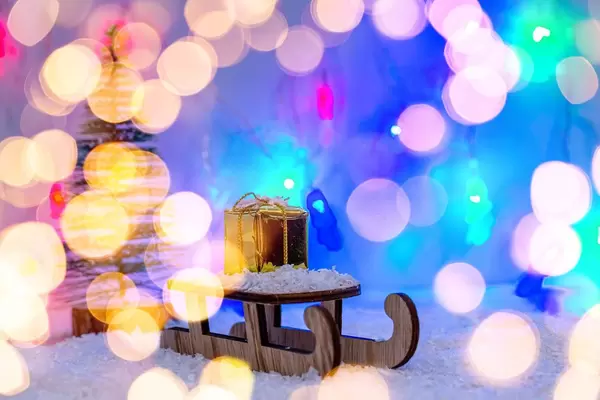 A sledge with a gift in the snow with a blurred background of glowing lights