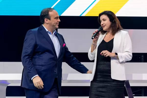 A smiling Hagen Rickmann, patron of the Digital X initiative, listens to the German Minister of State for Digitalization, Dorothee Bär, on the stage of the Koelnmesse