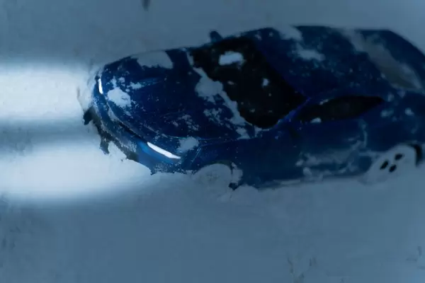 A sports car in dangerous driving conditions on a snowy road at dusk