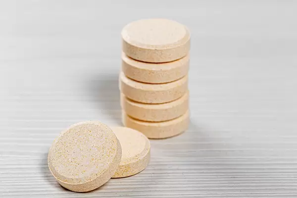 A stack of large pills on a white wooden background