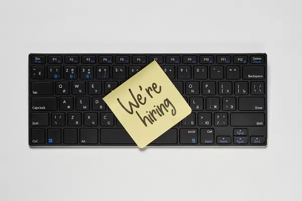 A sticky note on the pc keyboard with 'We are hiring' phrase