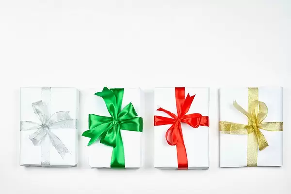 A straight row of four simple paper wrapped Christmas presents with colorful bows
