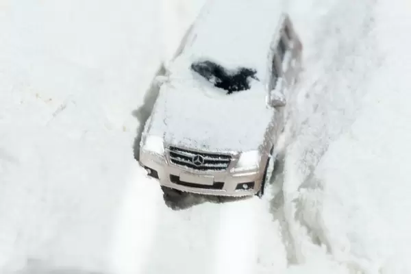 A terrain car is driving on a dirt road covered in snow