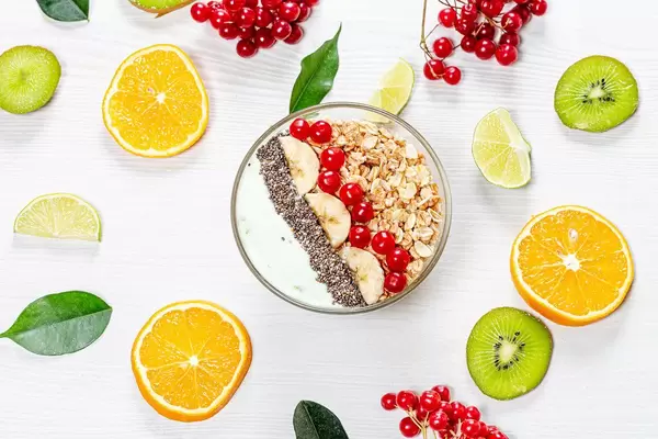 A top view of a bowl of oatmeal on a white wooden background with fresh fruits and berries (Flip 2019)