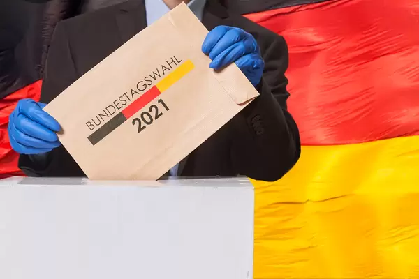 A voter putting a voting ballot into the election box over German flag