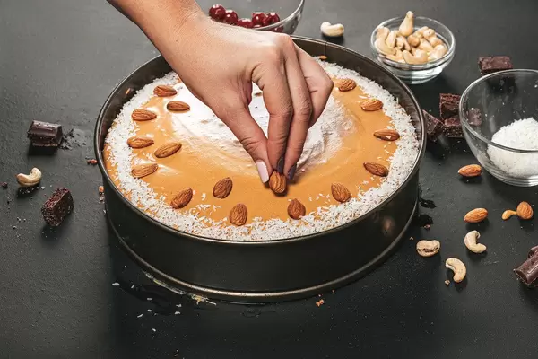 A woman decorates the cake with almonds. Birthday preparations (Flip 2019)
