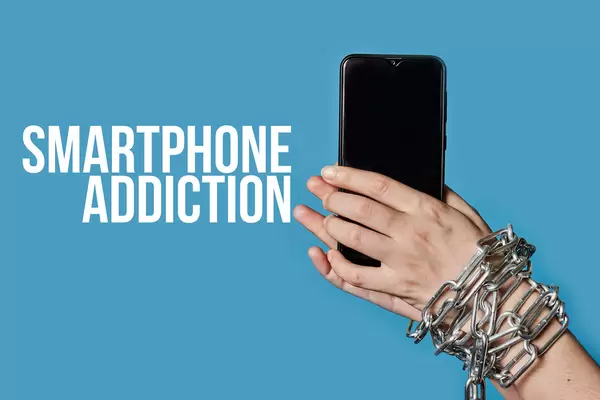 A woman hand in chain holding a mobile phone, as a symbol of smartphone addiction