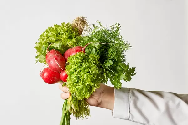 A woman holding a bunch of fresh radish and spring greenies
