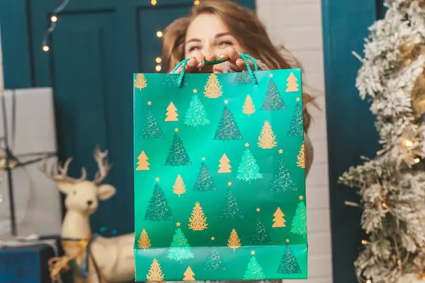 A woman holding a green gift bag in front of her