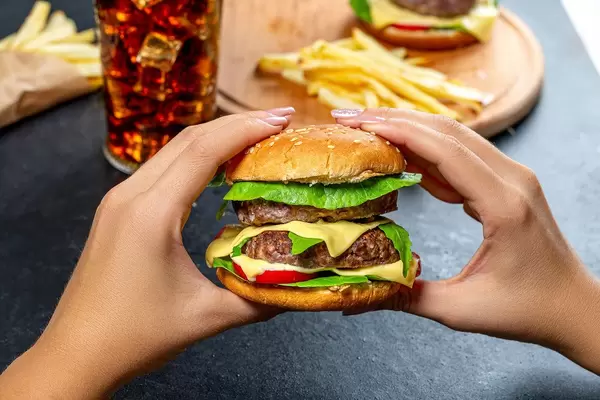 A woman holding a large hamburger on the background of fast food (Flip 2019)