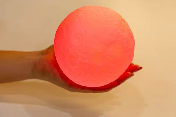 A woman holds a red glowing ball in her hand. Night light planet (Flip 2019)