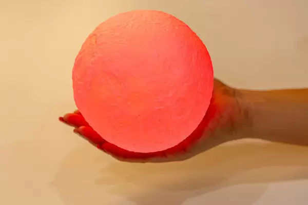 A woman holds a red glowing ball in her hand. Night light planet