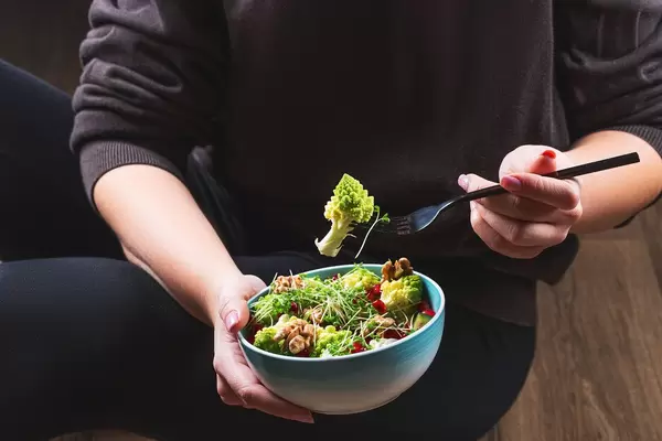 A woman in black clothes eating a vegetarian salad (Flip 2020)