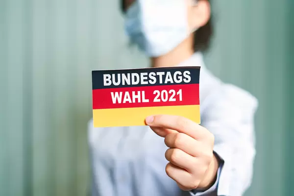 A woman in face mask holds German flag - Bundestagswahl 2021