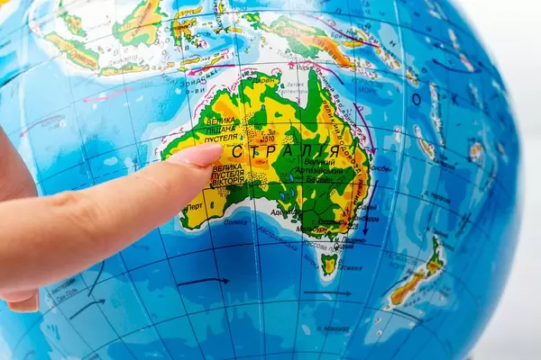 A woman points to Australia with her finger on a globe